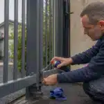 Portail qui grince ou se bloque : causes mécaniques et solutions sans démonter Homme peignant un portail métallique
